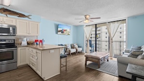 A modern kitchen with a central island, a dining area with a bench, and a living room with a sofa.
