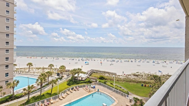 A hotel with a pool, beach view, and a clear sky.