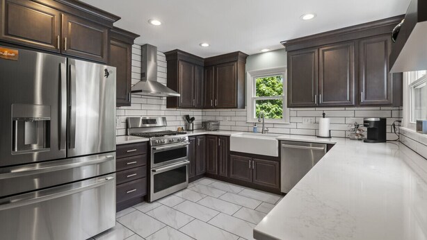 A modern kitchen with dark wood cabinets, stainless steel appliances, and a large window providing natural light. - Beautifully decorated, 15-20 min to downtown Cincy. (Cincinnati)