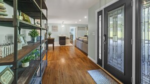 A hallway with wooden flooring, a black door with glass panels, and shelves with decorative items. - Beautifully decorated, 15-20 min to downtown Cincy. (Cincinnati)