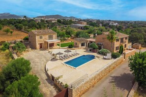A residential property with a swimming pool, stone buildings, and a view of the surrounding landscape.