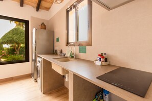 A modern kitchen with a built-in washer, a large window, and a countertop with a black induction cooktop.