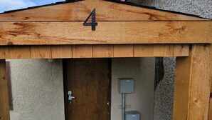 A wooden structure with a number '4' on the roof, a door, and a utility box. - 10 minute walk to restaurants & trails - Convenient Location - #4 Slumber Village (Anchorage)