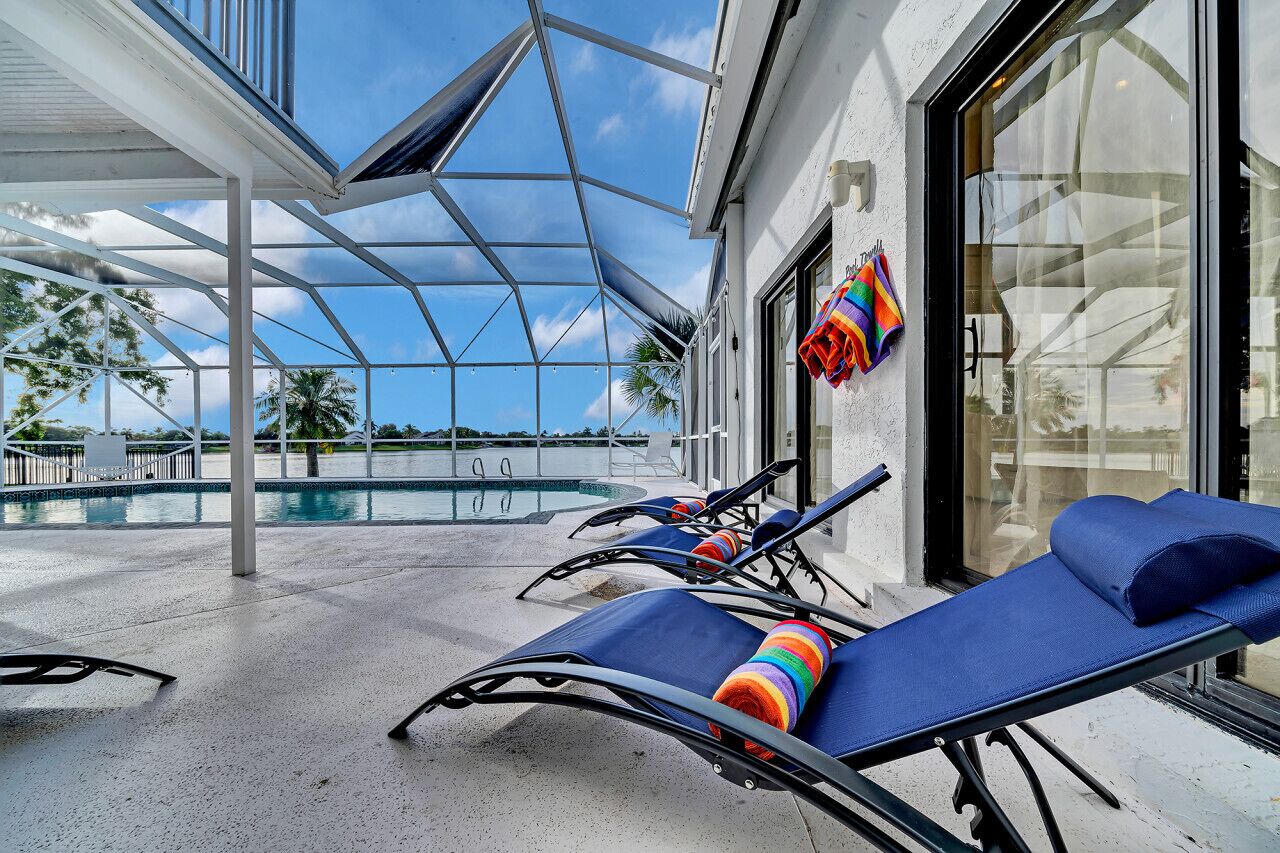 A poolside area with lounge chairs and a glass-enclosed patio.