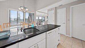 A modern kitchen with a black countertop, white cabinets, and a large window. - 3BR/2BA Cottage! Close to beach! Golf Course Views! Amenity access available! (Seabrook Island)