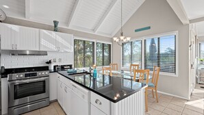 A modern kitchen with white cabinetry, a stainless steel stove, and a glass island with a sink. - 3BR/2BA Cottage! Close to beach! Golf Course Views! Amenity access available! (Seabrook Island)