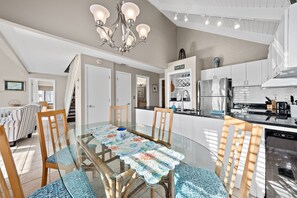 Une cuisine moderne avec une table à manger en verre, des chaises en bois et un lustre.