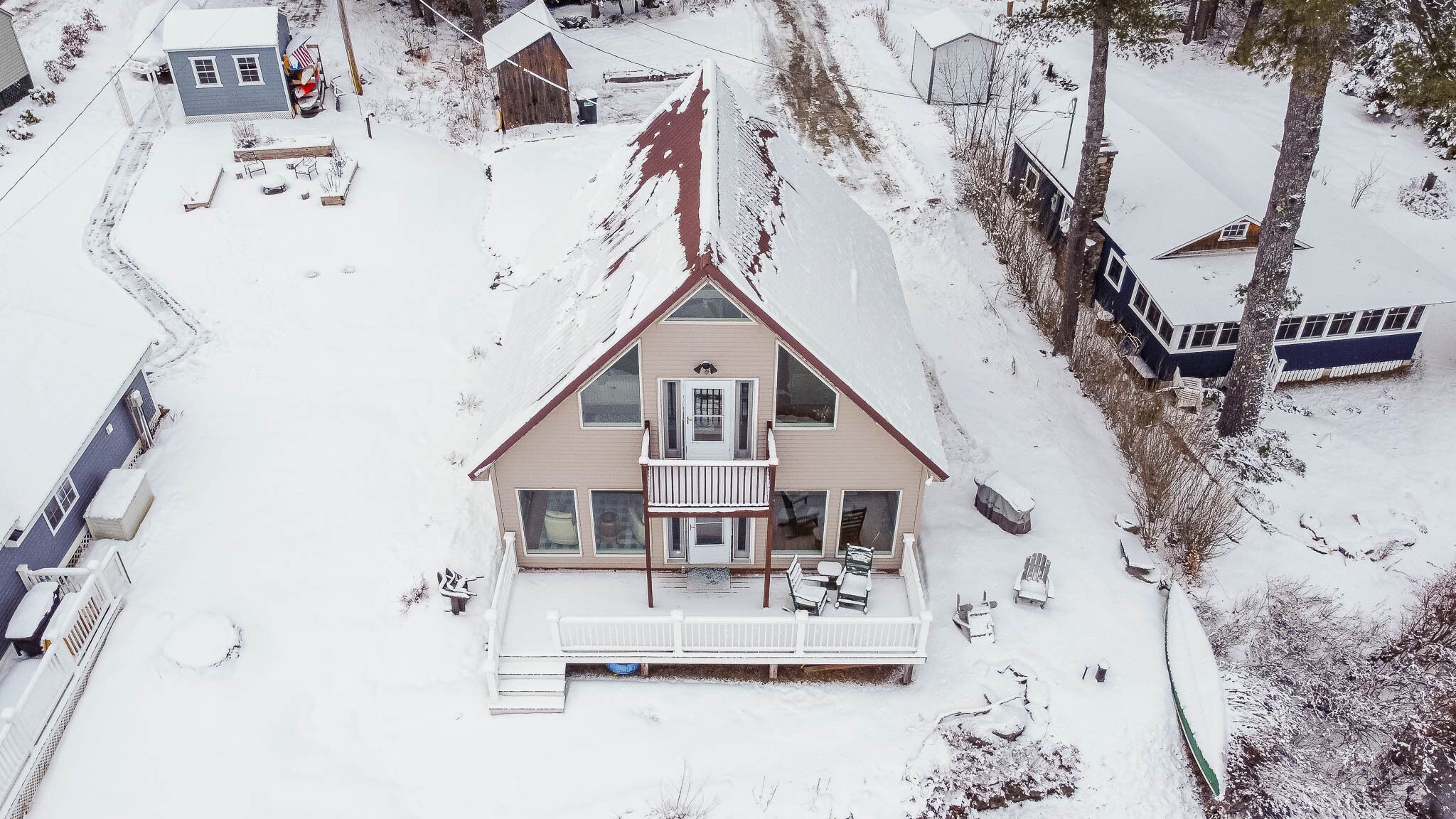 Ein zweistöckiges Haus mit Balkon, umgeben von verschneitem Gelände und Bäumen.