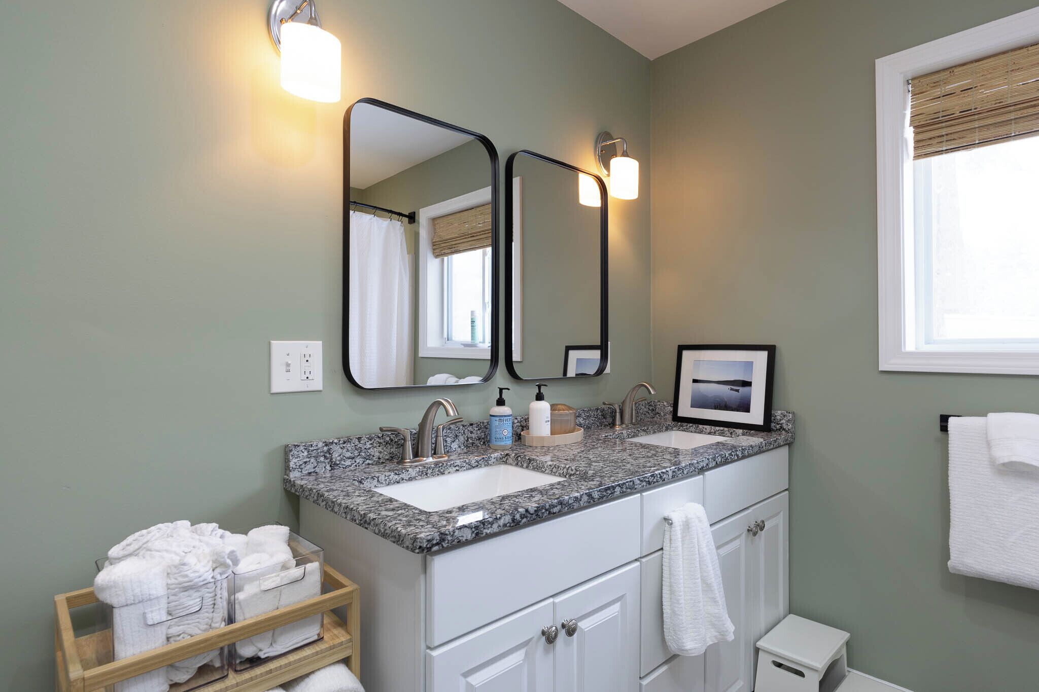 A bathroom with two sinks, a mirror, and a towel rack.