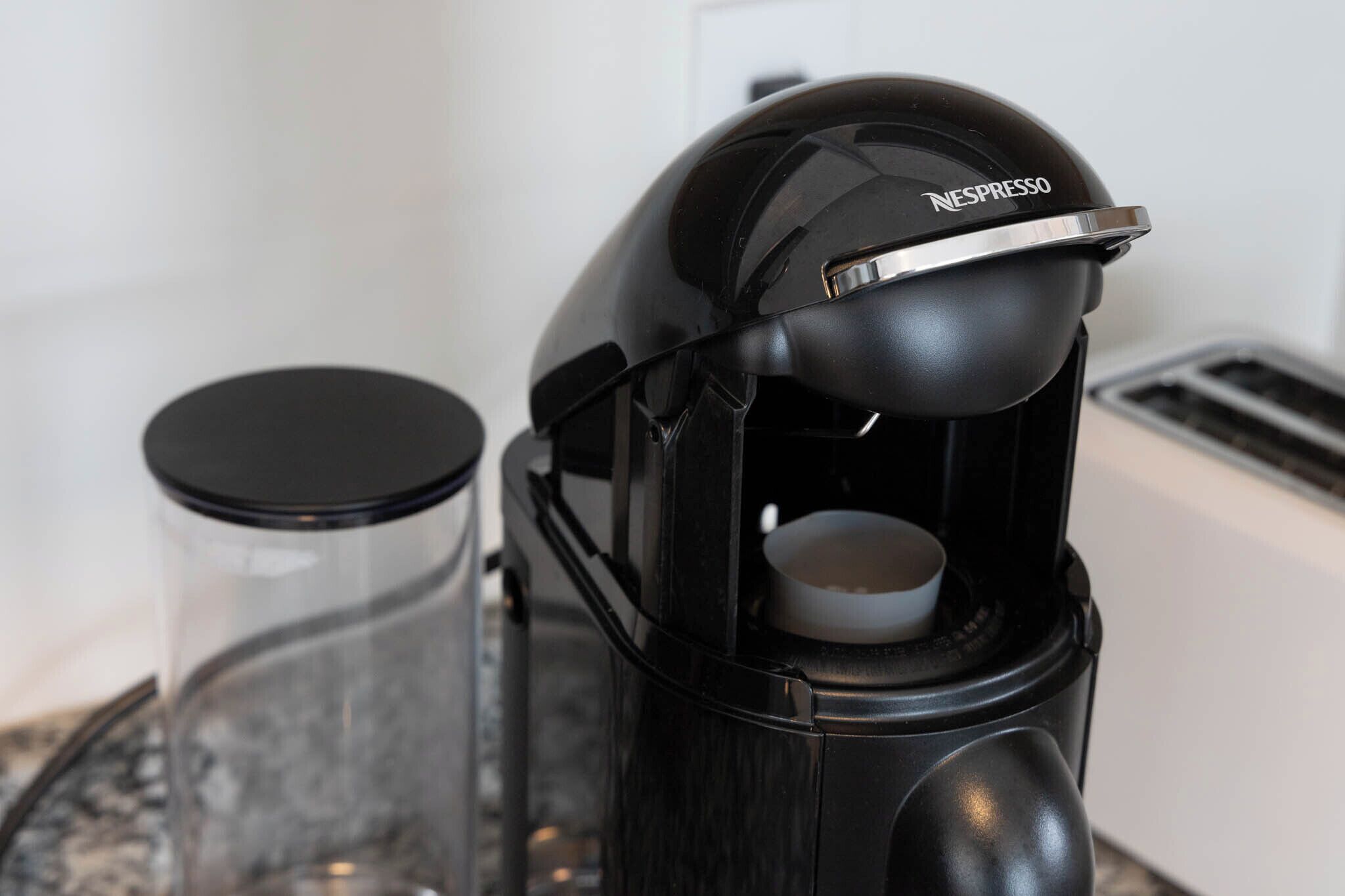 A Nespresso coffee machine with a glass carafe and a black lid.
