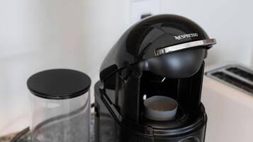 A Nespresso coffee machine with a glass carafe and a black lid.