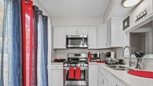 Una cocina moderna con armarios blancos, una estufa de acero inoxidable, un microondas y un lavabo.