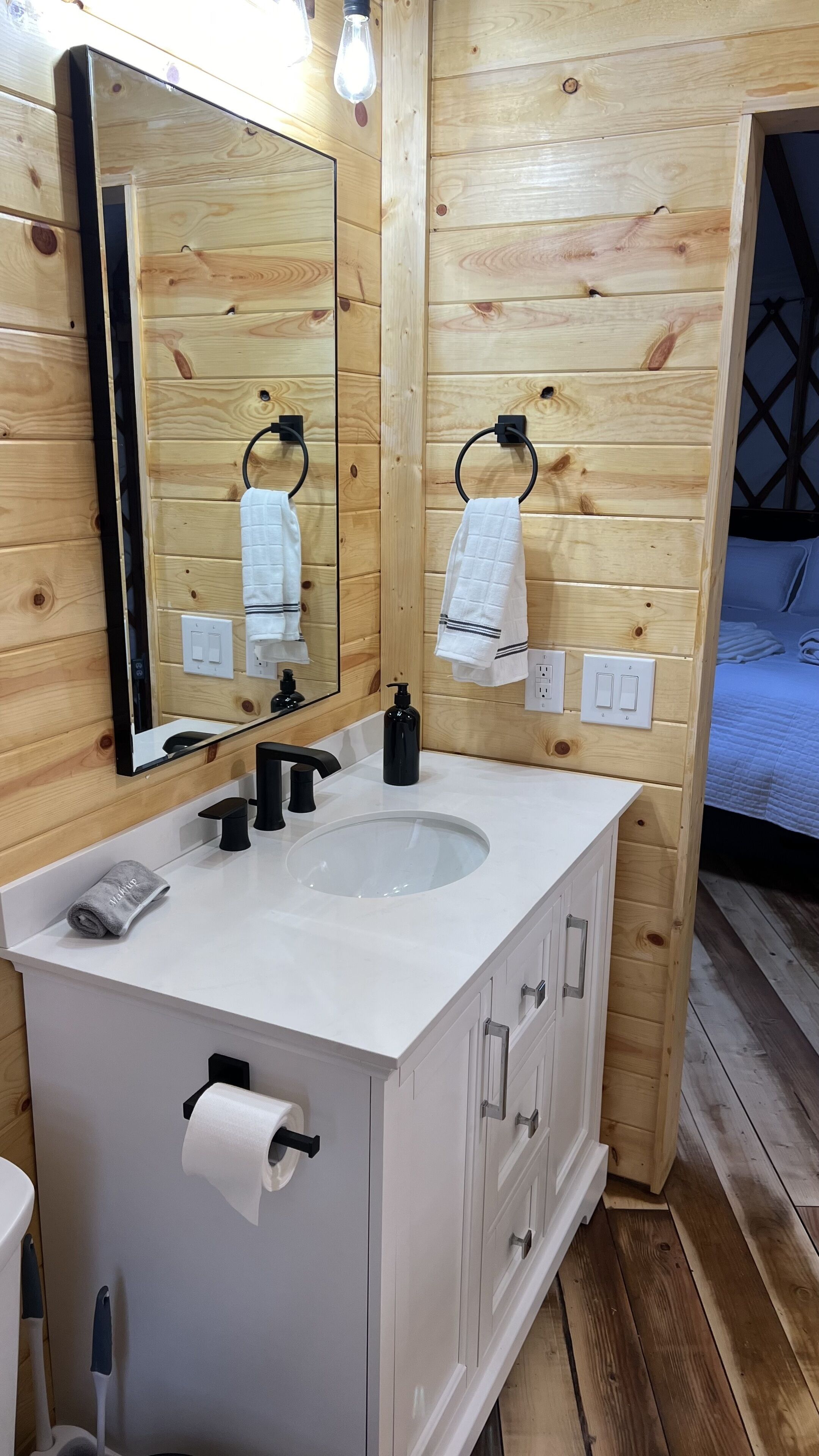 A wooden-paneled bathroom with a white vanity, a mirror, a sink, and a towel rack.