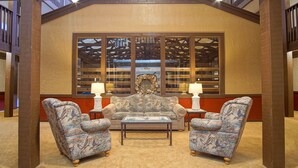 Un coin salon confortable avec un canapé et deux fauteuils, une petite table et deux lampes.
