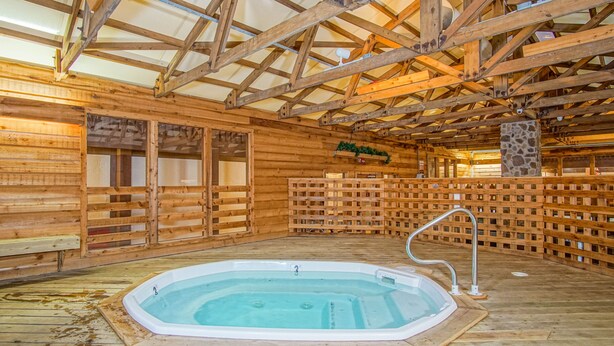 L’intérieur d’un chalet en bois doté d’un bain à remous, de murs en bois et d’un plafond haut.