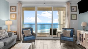 A room with a balcony overlooking the ocean, furnished with a sofa, two armchairs, and a table. - Oceanfront, Swimming Pool, 14th Floor Condo (Panama City Beach)