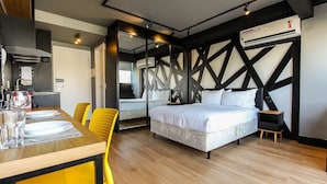 A modern room with a bed, a dining table with chairs, and a kitchen area.