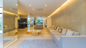 A modern living room with sofas, a coffee table, and a kitchen area visible through a glass partition.