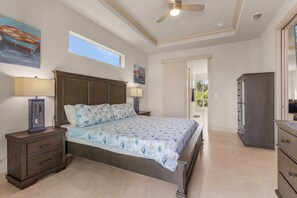 Ein Schlafzimmer mit einem Bett, Nachttischen, einer Kommode und einem Deckenventilator.
