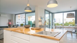 A modern kitchen with a wooden countertop, a sink, pendant lights, and a view of the outdoors. - CASA DEL MAR - Villa with sea views and private pool close to the beach - Free Wi-Fi (Santa Margalida)