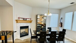 A dining area with a fireplace, a foosball table, and a dining table with chairs. - Discover Turlock charm near California State University  (Turlock)