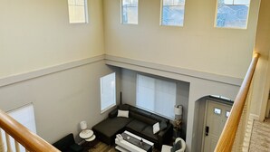 A spacious living area with a sofa, a coffee table, and a lamp. There are three windows providing natural light. - Discover Turlock charm near California State University  (Turlock)