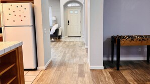 A kitchen with wooden cabinets, a white refrigerator, and a wooden table with a foosball table. - Discover Turlock charm near California State University  (Turlock)