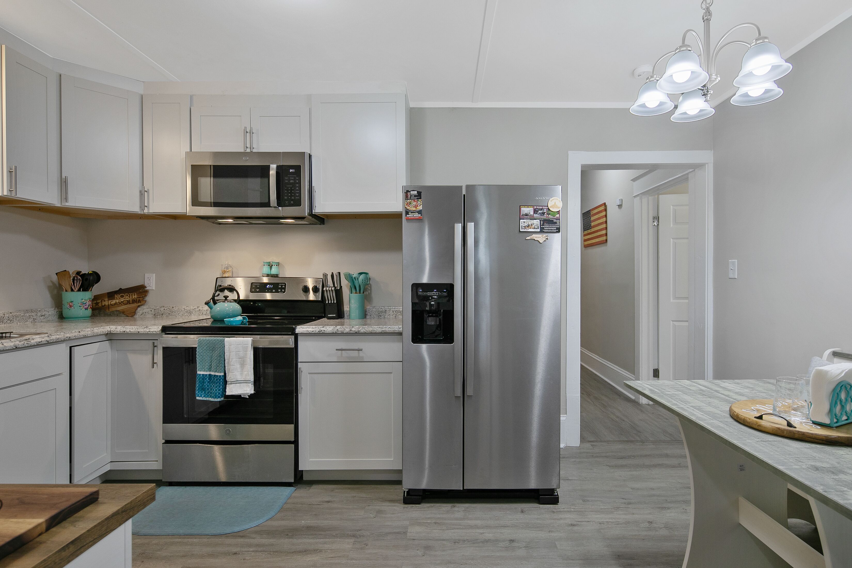 A modern kitchen with stainless steel appliances, white cabinetry, and a wooden countertop.