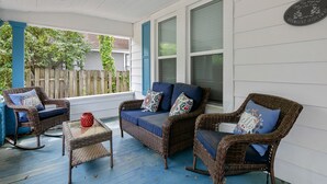A covered porch with wicker furniture, a glass table, and a red candle. - Your Newest, Remodeled, and Fully-Furnished AirB&B in the Heart of Fayetteville! (Fayetteville)