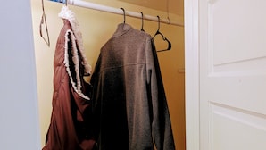 Ein Schrank mit zwei an einem Kleiderbügel aufgehängten Mänteln.