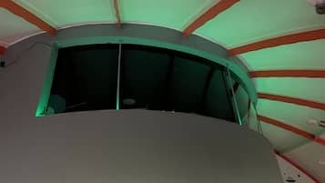 Ein Zimmer mit gewölbter Decke, einer sichtbaren Leuchte und einem teilweisen Blick aus einem Fenster.