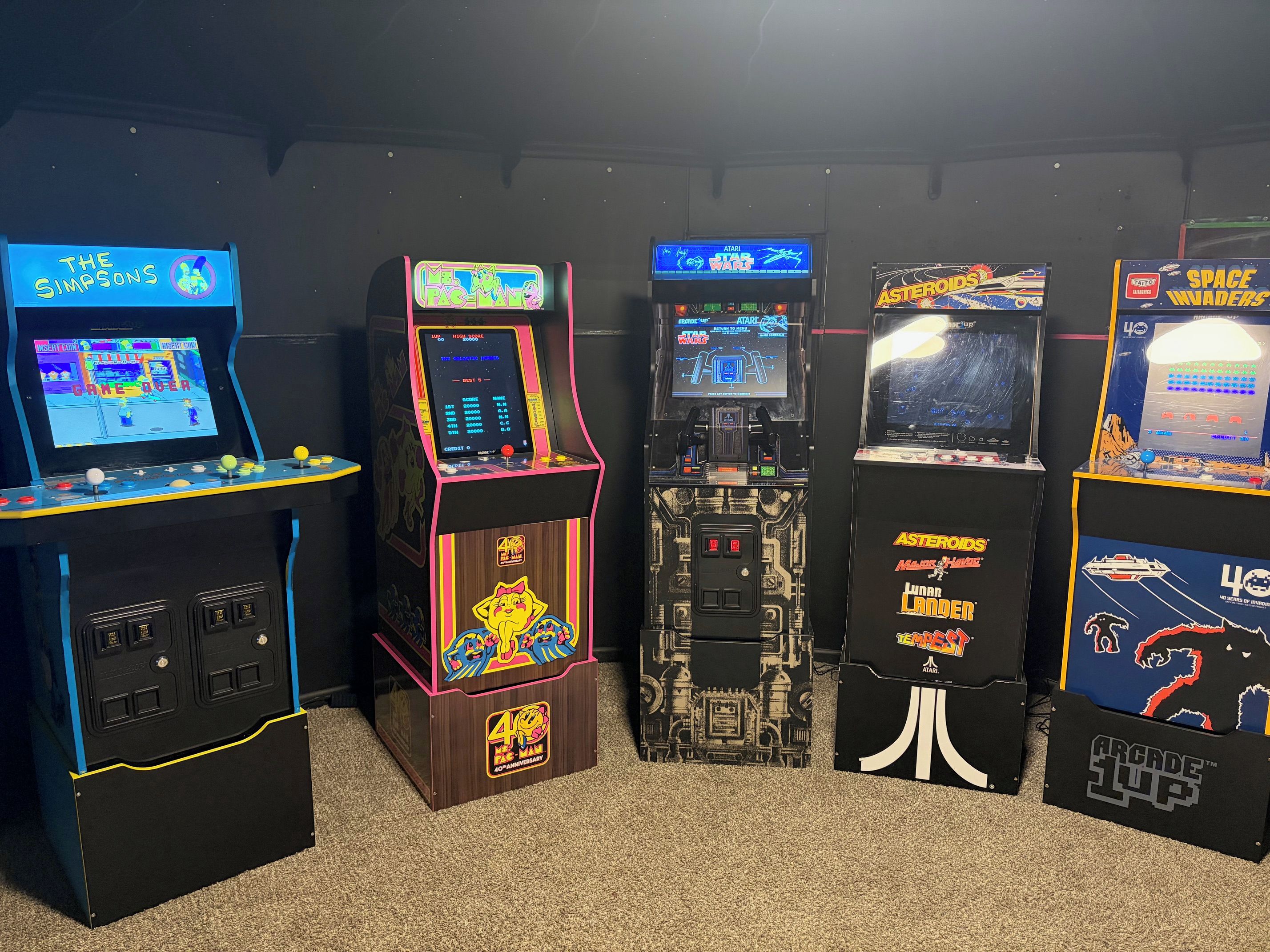 Una hilera de máquinas de arcade con varios juegos, incluyendo 'The Simpsons' y 'Star Wars'.