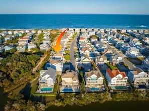 Vista aérea de una zona residencial costera con casas, una carretera y una masa de agua.
