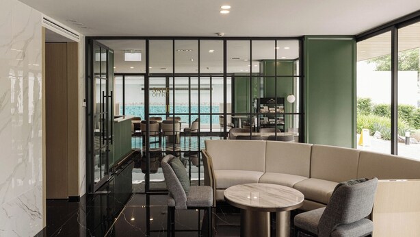 A modern interior with a glass partition, a pool area, and a seating area with a round table. - Cha Chiangmai Luxury (Chiang Mai)