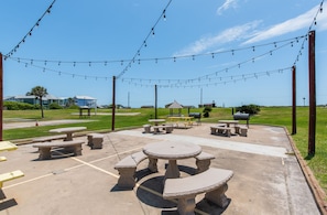 An outdoor patio with picnic tables and string lights. - IR141 Walk to Sandfest, Shared Pools, Boardwalk to the Beach (Port Aransas)