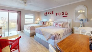 Habitación de hotel con temática playera, con dos camas, una mesa de comedor y vista al mar.