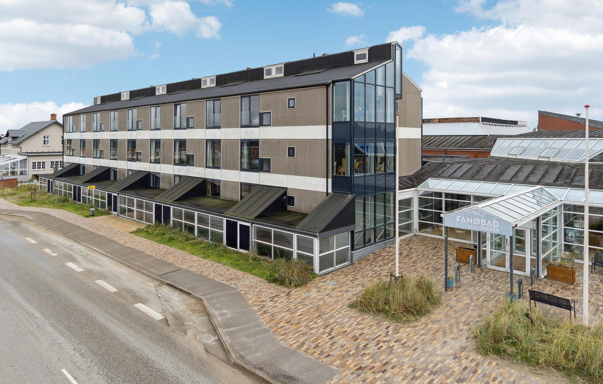 Een modern gebouw met een glazen gevel, een overdekt terras en een bord met de tekst 'Fanåbad'.