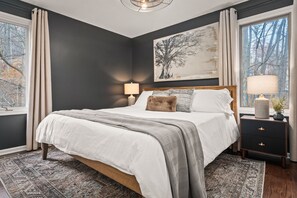 A bedroom with a large bed, two bedside tables, a nightstand, and a window with curtains. - 7BR Designer Home in Massanutten (McGaheysville)
