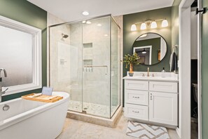 A modern bathroom with a glass-enclosed shower, a freestanding bathtub, and a vanity with a mirror. - 7BR Designer Home in Massanutten (McGaheysville)