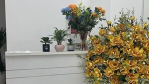 A reception desk with a white surface, a small potted plant, and a large vase with yellow flowers. - Huyen Anh Hotel (Hanoi)