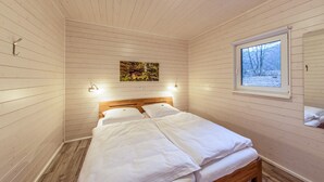 A bedroom with a wooden bed, a window with a view of trees, and a painting on the wall. - Stunning home in Ruhla with sauna (Ruhla)