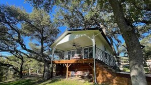 A two-story house with a balcony, surrounded by trees.