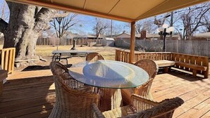 Eine überdachte Terrasse im Freien mit Korbmöbeln und einem Glastisch.