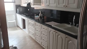 A kitchen with white cabinets, a black countertop, a sink, and a stove. - Edificio san thelmo laureles  (Medellín)