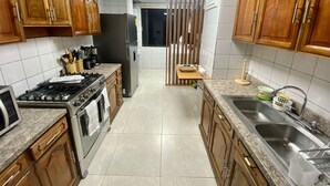 Eine Küche mit Holzschränken, einem Edelstahlspülbecken, einem Kühlschrank und einem Herd.