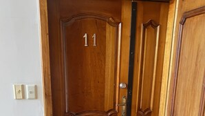 Eine hölzerne Doppeltür mit der Nummer 11, einem Metallgriff und einer verzierten Fußmatte aus Metall.