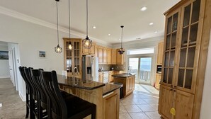 A spacious kitchen with wooden cabinets, a granite countertop, and pendant lighting. - “Coastal Haven” Gorgeous 6 bedroom home pool (North Topsail Beach)