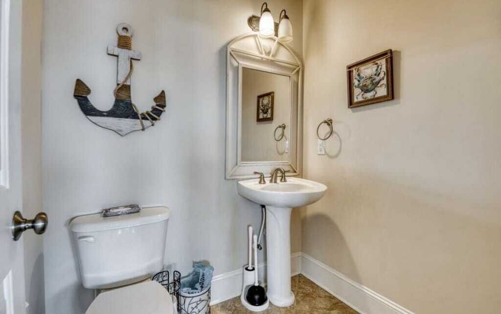 Une salle de bain équipée de toilettes, d’un lavabo et d’un luminaire fixé au mur.