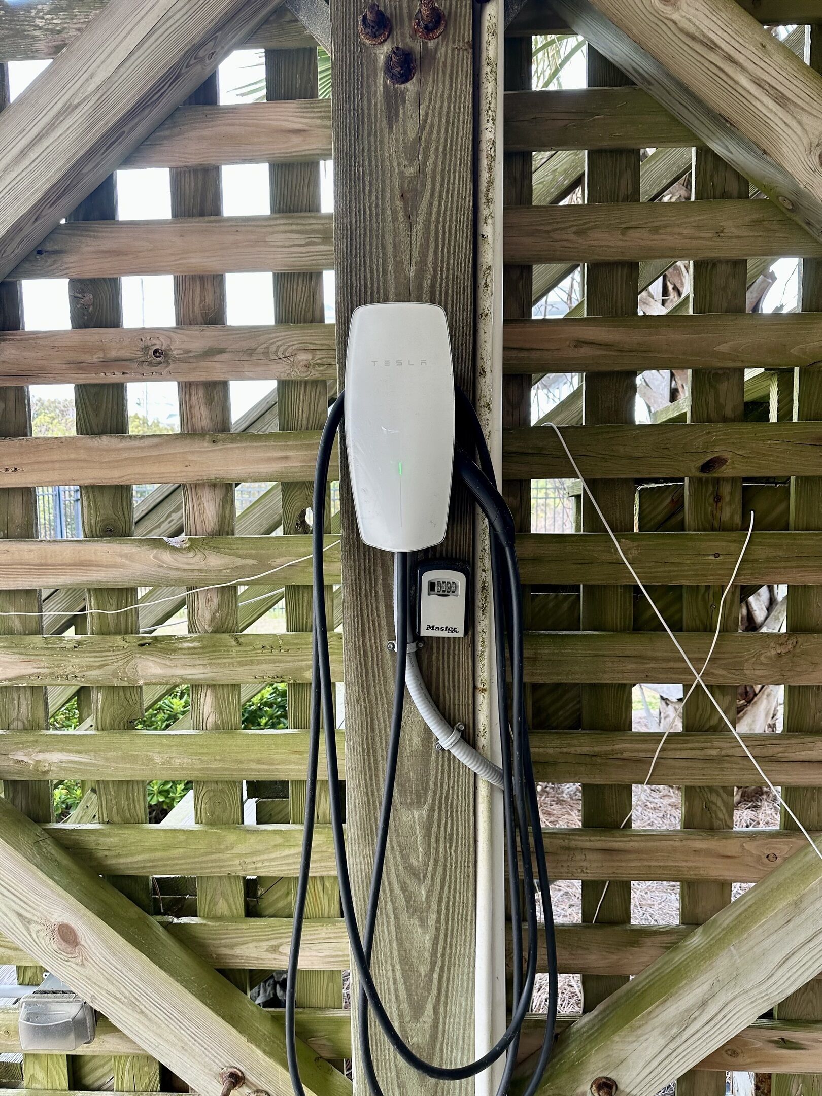 Eine Tesla-Ladestation an einer Holzkonstruktion mit Gittermuster.