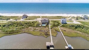 A coastal property with a large house, a smaller building, and a dock extending into a body of water. - “Coastal Haven” Gorgeous 6 bedroom home pool (North Topsail Beach)